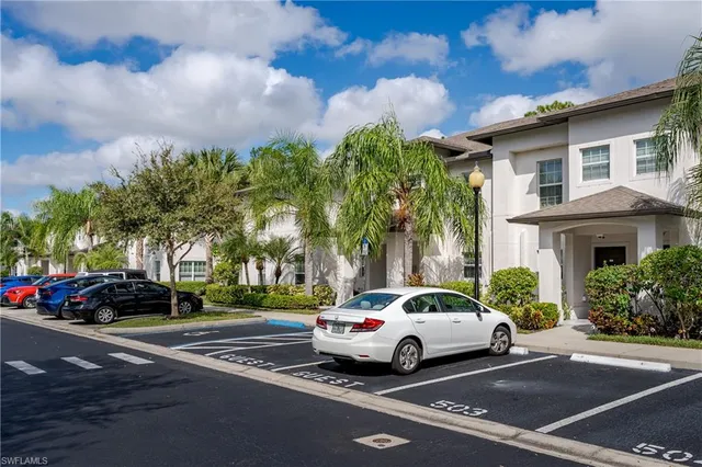 a view of road with card parked on side and retail shops
