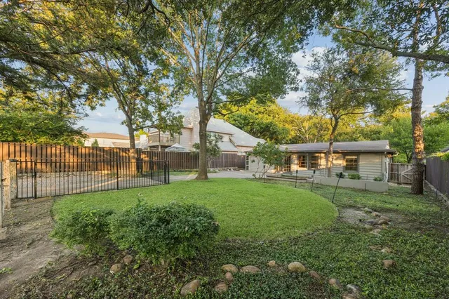 a view of a yard in front of a house with a large tree