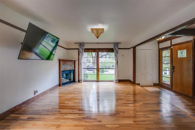 a view of an empty room with window and wooden floor