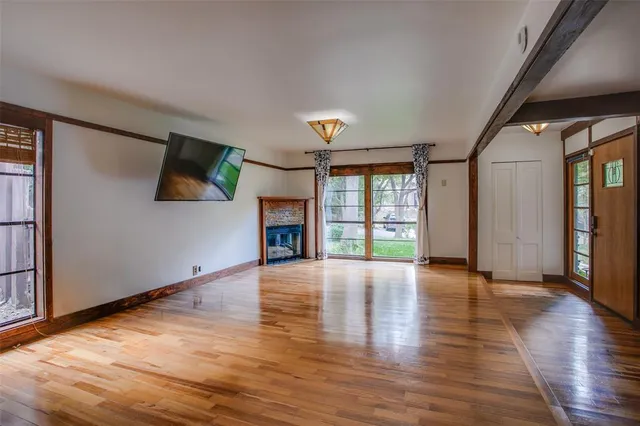 a view of an empty room with window and wooden floor