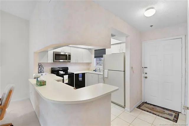 a kitchen with stainless steel appliances a microwave a stove a refrigerator and white cabinets