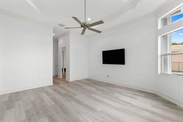 a view of an empty room with window and wooden floor