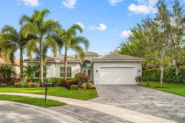 a view of a white house with a yard and palm trees