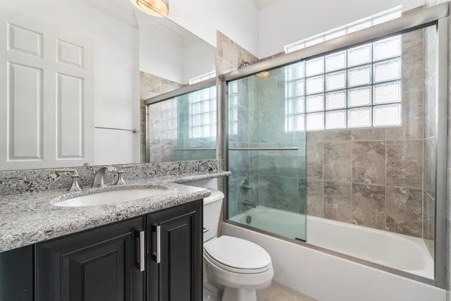 a bathroom with a granite countertop sink toilet and shower