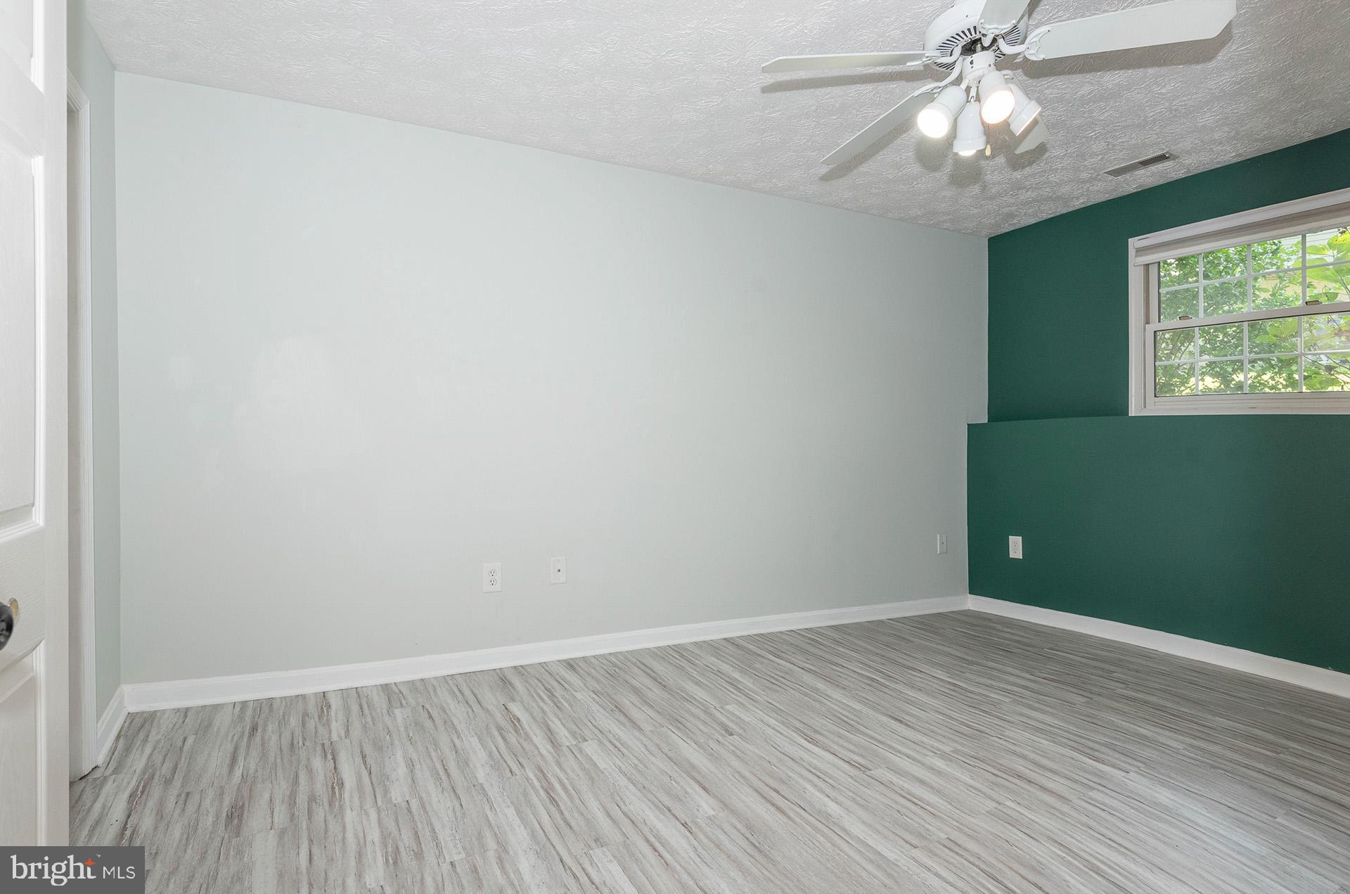 7523 Harmans Road Harmans, MD 21077 - Photo 21 of 27 an empty room with wooden floor chandelier fan and windows