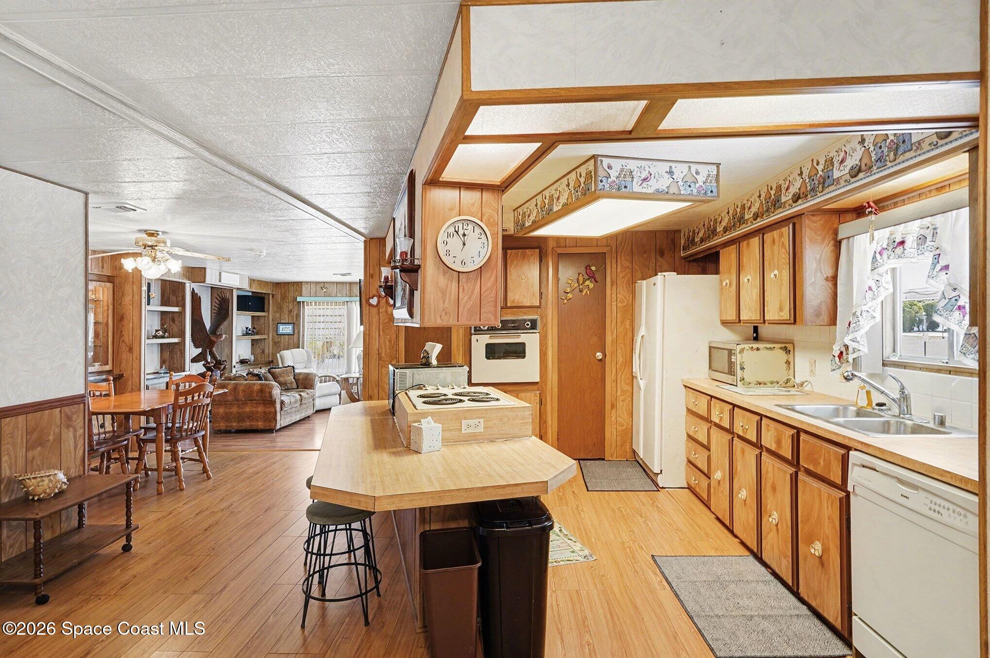 1740 Coco Plum Street Northeast Palm Bay, FL 32905 - Photo 13 of 33 a kitchen with stainless steel appliances a stove a sink dishwasher and a dining table with wooden floor