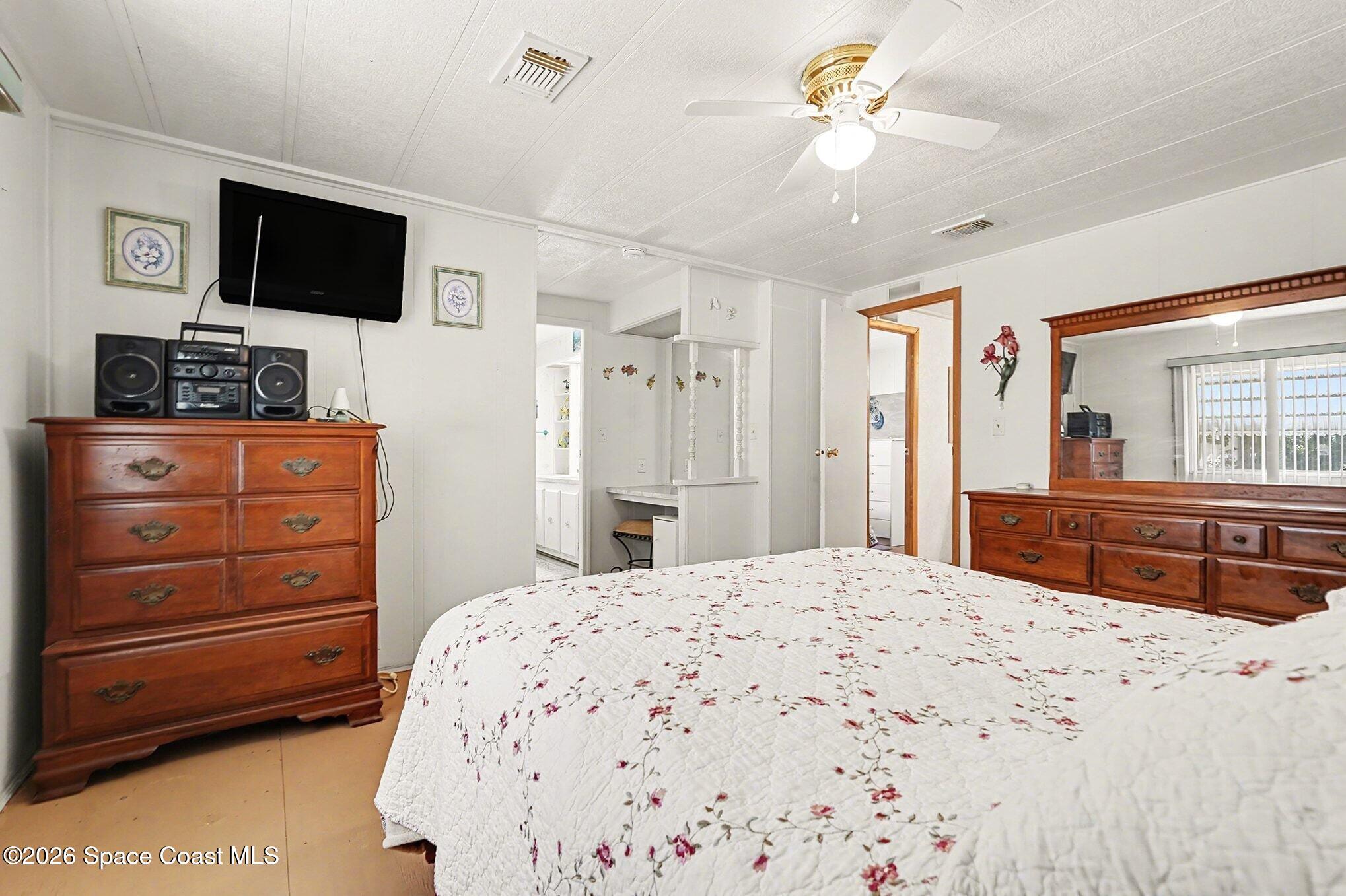 1740 Coco Plum Street Northeast Palm Bay, FL 32905 - Photo 21 of 33 a bedroom with a bed a flat screen tv and a dresser