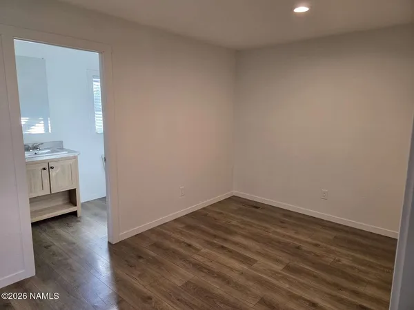 an empty room with wooden floor and a bathroom