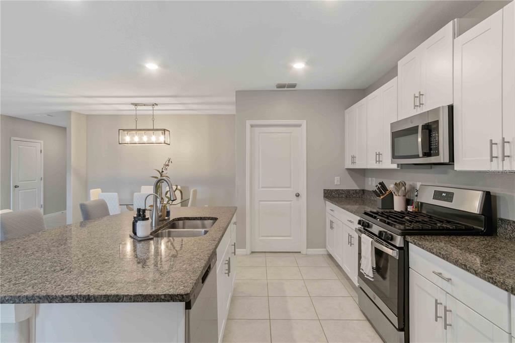 9440 Lemon Drop Loop Sun City Center, FL 33573 - Photo 14 of 55 a kitchen with stainless steel appliances granite countertop a sink stove and cabinets