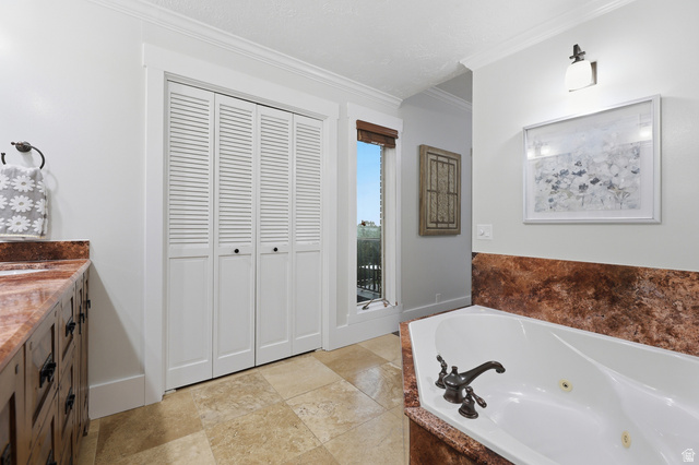 2342 Charros Road Sandy, UT 84092 - Photo 36 of 94 Bathroom featuring a built-in jetted tub with a reddish-brown stone surround, a vanity with a reddish-brown stone countertop, tile flooring, and white louvered bifold doors