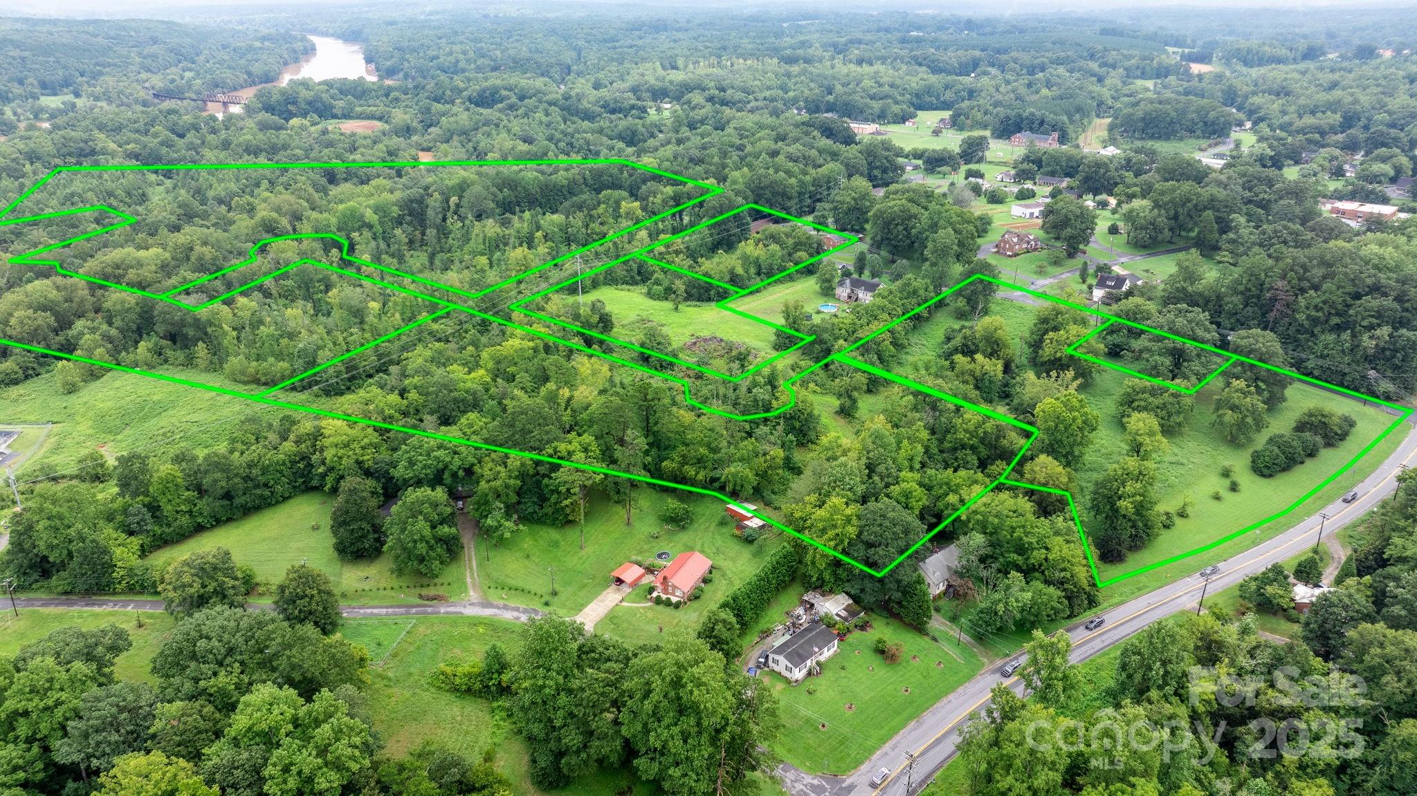 an aerial view of residential house with outdoor space and trees all around