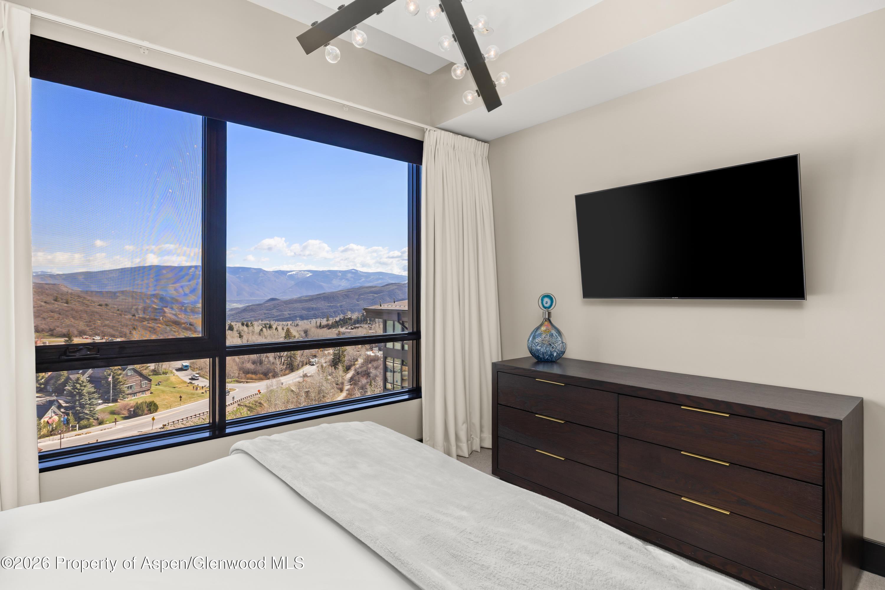 77 Wood Road, Unit 703 EAST Snowmass Village, CO 81615 - Photo 10 of 21 a living room with a large window and a flat screen tv