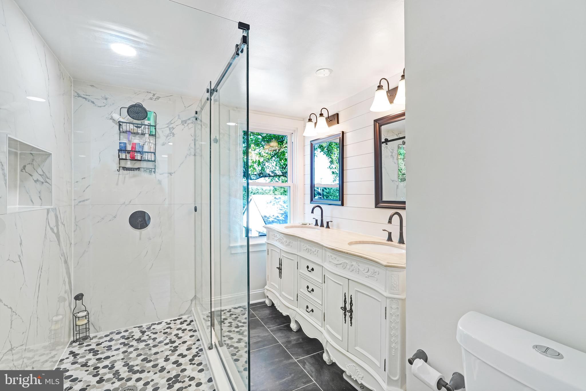 27100 Ridge Road Damascus, MD 20872 - Photo 31 of 74 a bathroom with a double vanity sink a toilet a shower and a mirror
