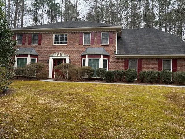 a front view of house with yard and trees in the background