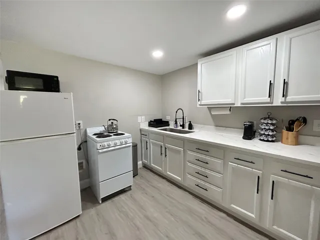 a kitchen with white cabinets a sink and white appliances
