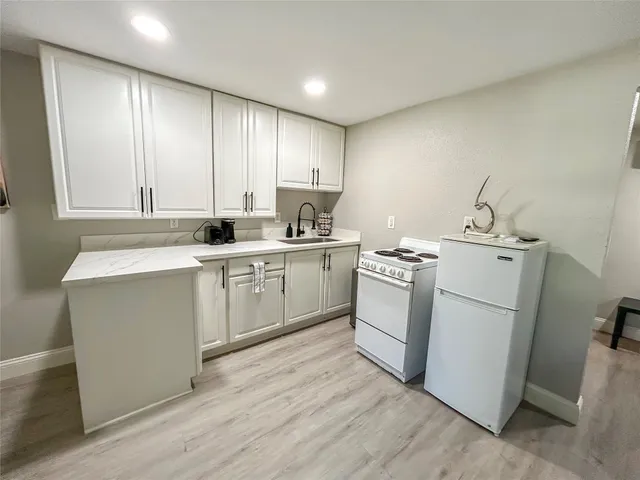 a kitchen with a sink white cabinets and white appliances