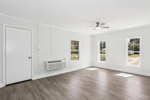 a view of an empty room with a window and wooden floor