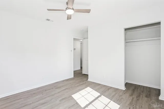 an empty room with wooden floor closet and windows