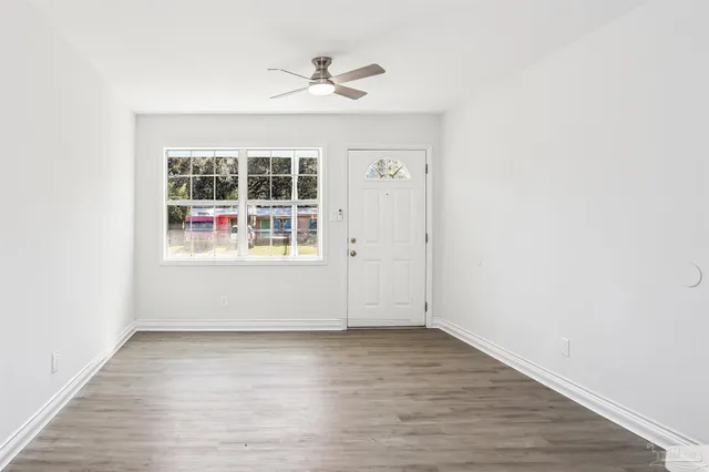 an empty room with wooden floor and windows