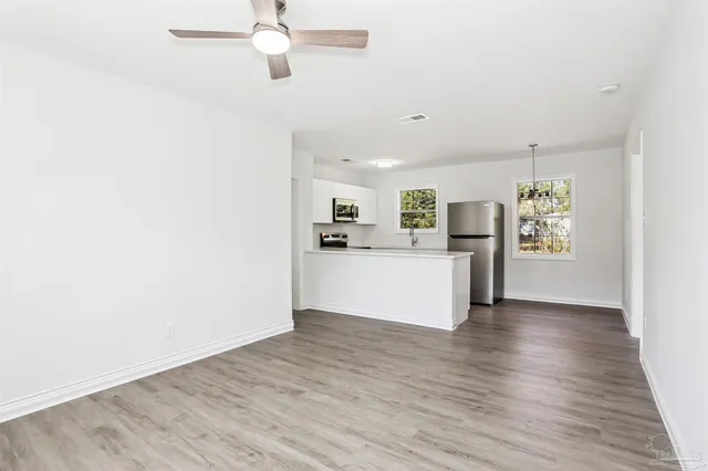 a view of a kitchen with wooden floor electronic appliances and window