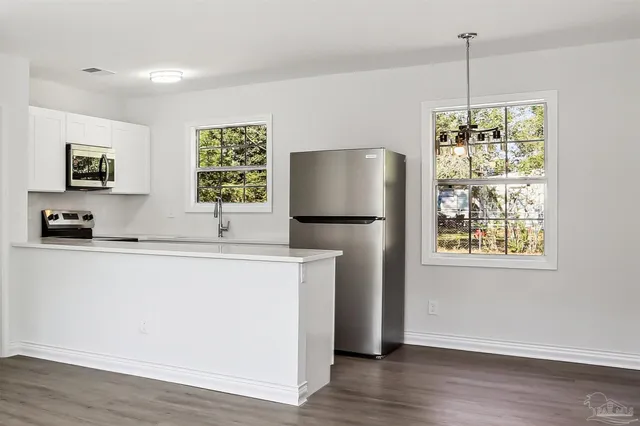 a kitchen with stainless steel appliances granite countertop a refrigerator a stove a microwave oven a sink and dishwasher with wooden floor