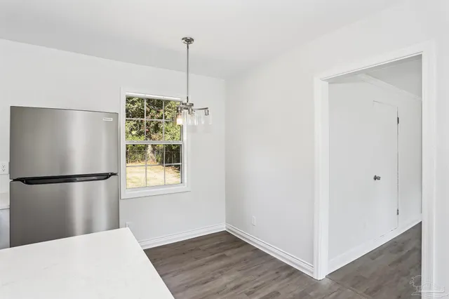 a view of a kitchen with a fridge and wooden floor