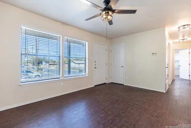 a view of an empty room with a window and wooden floor