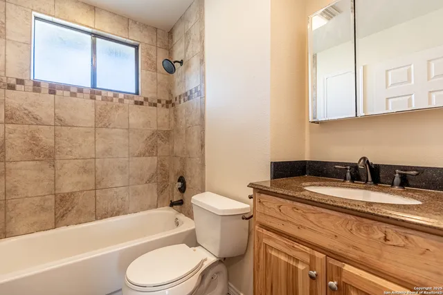 a bathroom with a granite countertop toilet sink and mirror