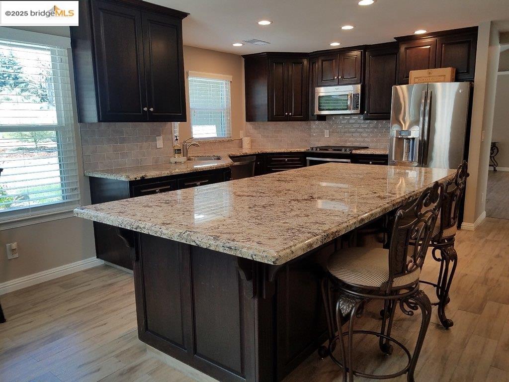 1740 South Teddy Street Visalia, CA 93277 - Photo 5 of 24 a kitchen with stainless steel appliances granite countertop a table chairs sink refrigerator and microwave