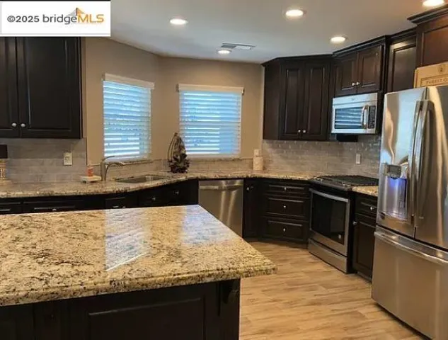 a kitchen with stainless steel appliances granite countertop a sink stove and refrigerator