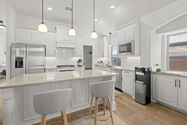 a open kitchen with stainless steel appliances granite countertop a kitchen island a stove a sink dishwasher a dining table and chairs with wooden floor