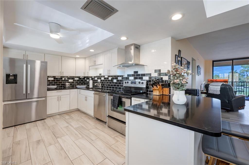 413 Augusta Boulevard, Unit 302 Naples, FL 34113 - Photo 13 of 39 a kitchen with stainless steel appliances granite countertop a stove a refrigerator a sink a counter space and chairs