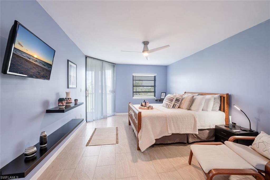 413 Augusta Boulevard, Unit 302 Naples, FL 34113 - Photo 24 of 39 a spacious bedroom with a bed and a flat screen tv