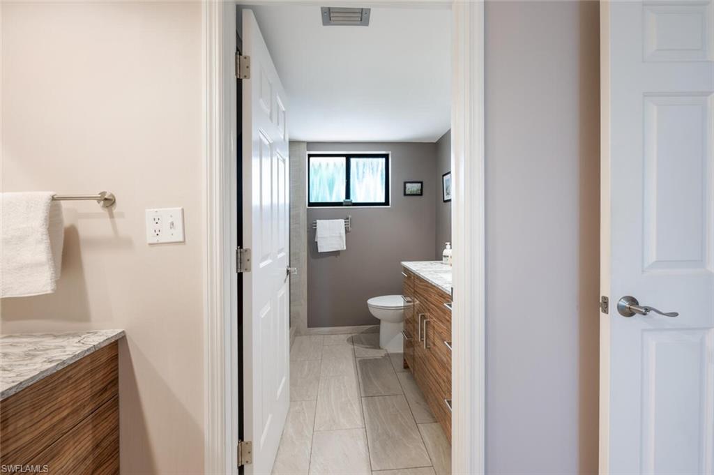 413 Augusta Boulevard, Unit 302 Naples, FL 34113 - Photo 27 of 39 a bathroom with a granite countertop sink a toilet and a shower