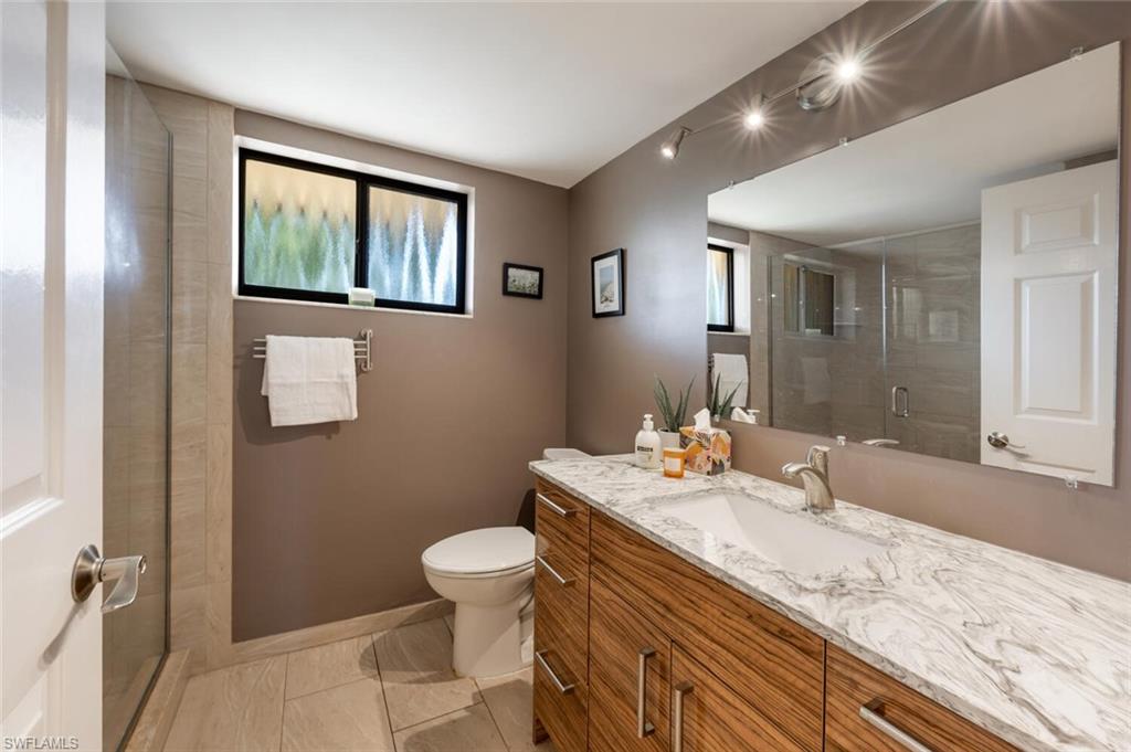 413 Augusta Boulevard, Unit 302 Naples, FL 34113 - Photo 28 of 39 a bathroom with a granite countertop sink a toilet and a mirror