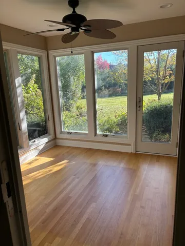 a view of empty room with wooden floor and fan
