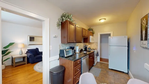 a kitchen with stainless steel appliances granite countertop a refrigerator a stove a sink dishwasher and a dining table with wooden floor