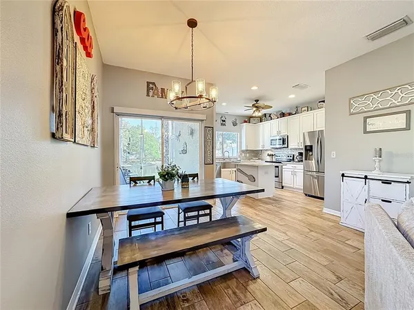 a view of a kitchen with kitchen island stainless steel appliances wooden floor dining table and chairs