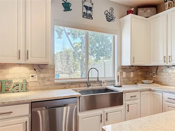 a kitchen with granite countertop a sink window and cabinets