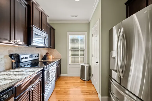 a kitchen with stainless steel appliances granite countertop a refrigerator a stove and a sink with wooden floor