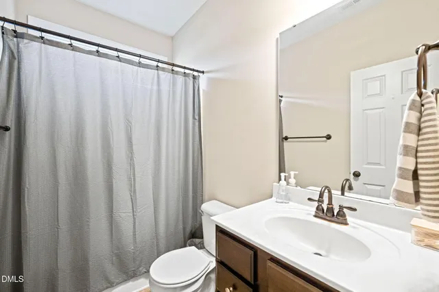 a bathroom with a sink a toilet and shower curtain