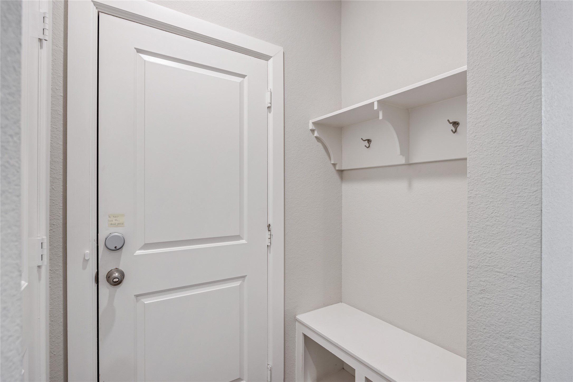 3604 Magnolia Crest Lane Spring, TX 77386 - Photo 10 of 50 This entryway from the garage features a clean, white aesthetic with a door leading outside, a built-in bench, and wall hooks for coats, providing a functional and welcoming space.