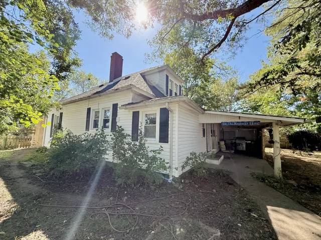 a view of a backyard with a large tree and wooden fence