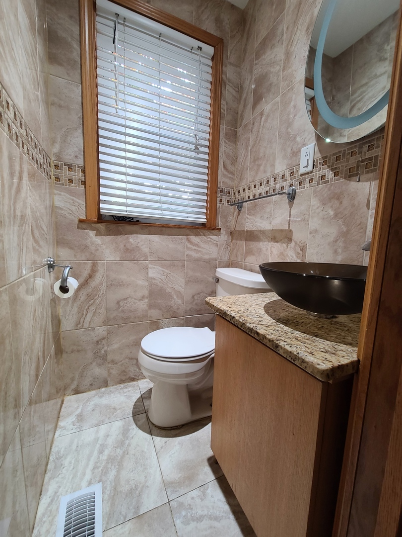 3801 West 63rd Place Chicago, IL 60629 - Photo 14 of 36 a bathroom with a granite countertop toilet sink and mirror