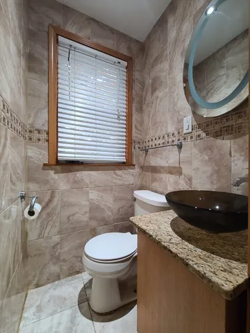 a bathroom with a granite countertop toilet a sink and a mirror