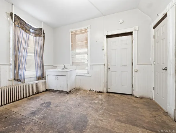 an empty room with a window and a kitchen