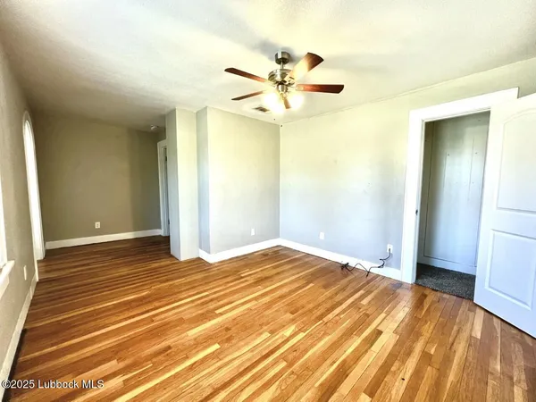 a view of a livingroom with wooden floor and a ceiling fan