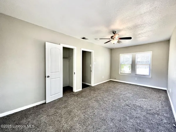 an empty room with fan and windows