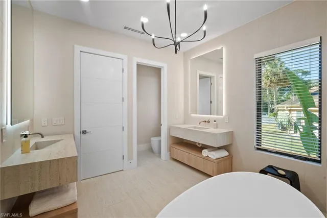 a bathroom with double vanity sink a two mirror a window and a bathtub