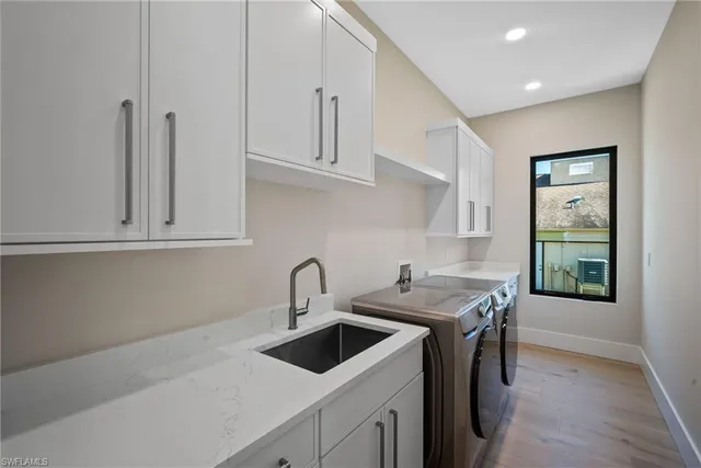 a kitchen with stainless steel appliances a sink a stove and white cabinets with wooden floor